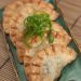 Platter of Jamaican beef dumplings garnished with scallion curls.