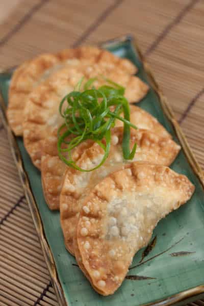 Platter of Jamaican beef dumplings garnished with scallion curls.