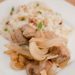 A plate of pork tenderloin with apples and onions served with rice.