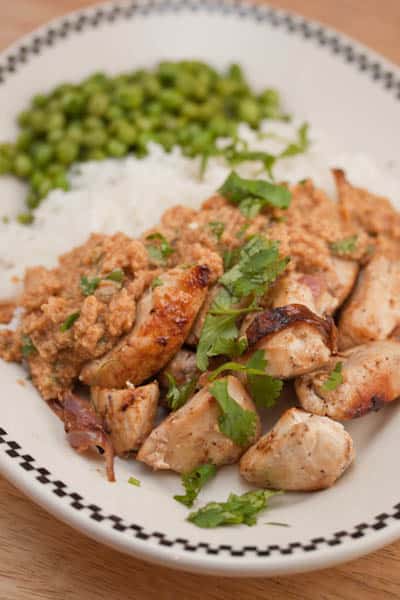 A plate of chicken with rice and peas.
