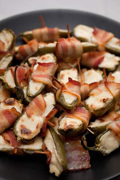 Overhead view of a pile of bacon-wrapped japapeños stuffed with cream cheese.