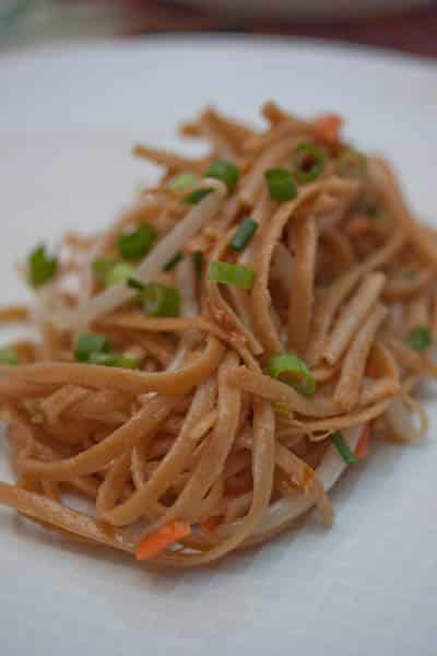 Close-up of a Thai noodle salad topped with green onions.