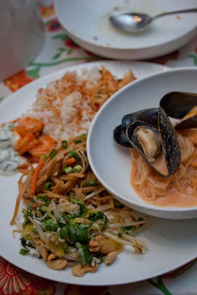 Assortment of Thai food including noodles, shrimp, rice, and mussels.