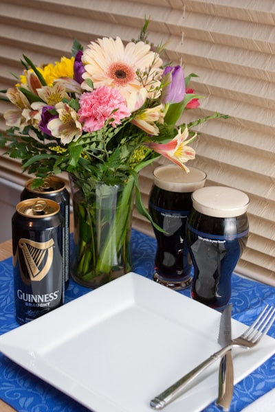 Empty plate with utensils, pints of Guinness, and a bouquet of flowers.