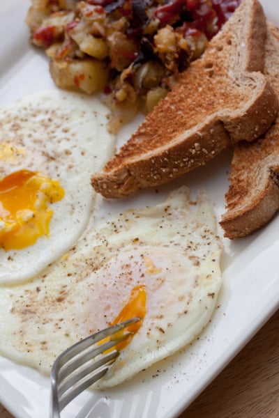 A plate of eggs with toast and home fries.