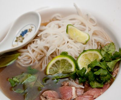 A bowl of pho with fresh herbs and lime.
