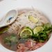A bowl of pho with fresh herbs and lime.