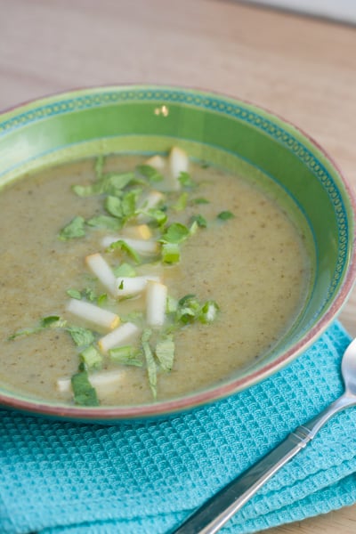 Bowl of celery and pear bisque with a spoon.