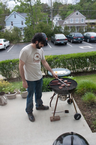 A man grilling burgers and hot dogs.