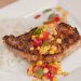 Pork chop with colorful veggies on top served with rice.