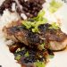 A plate of pork chops with rice and black beans.