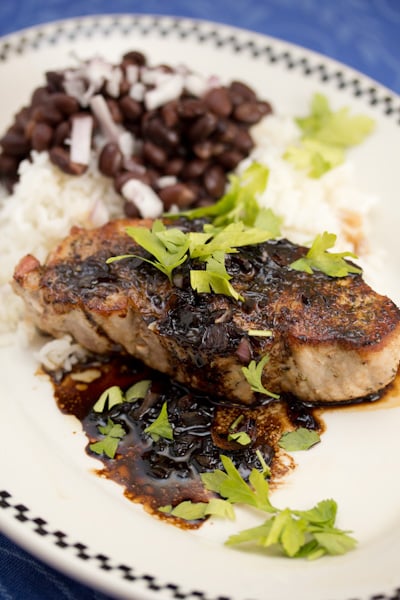 A plate of pork chops with rice and black beans.