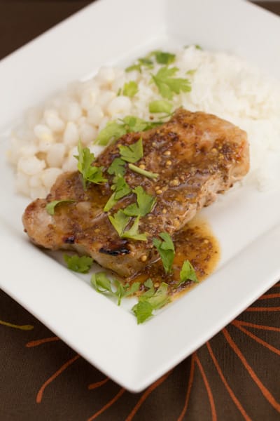 A plate of pork chops with rice and hominy.