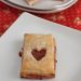 Pastries with hearts cut out of the top revealing red jam underneath.