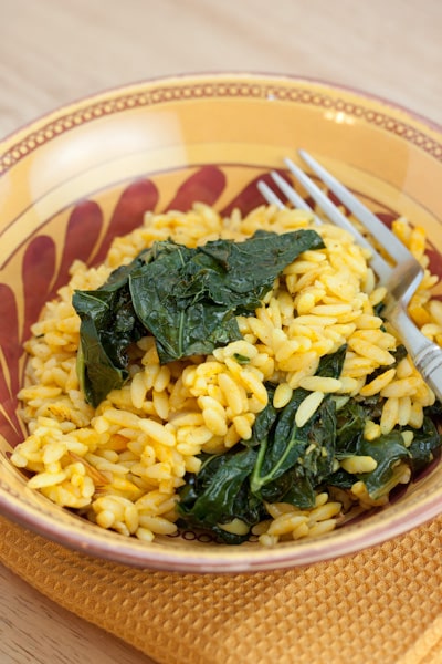 Orzo with cooked kale in a bowl with a fork.