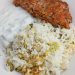 Presian meatloaf on a dish with dill rice and yogurt sauce.