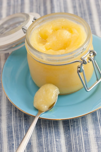 Lemon curd in a jar with a spoonful alongside.