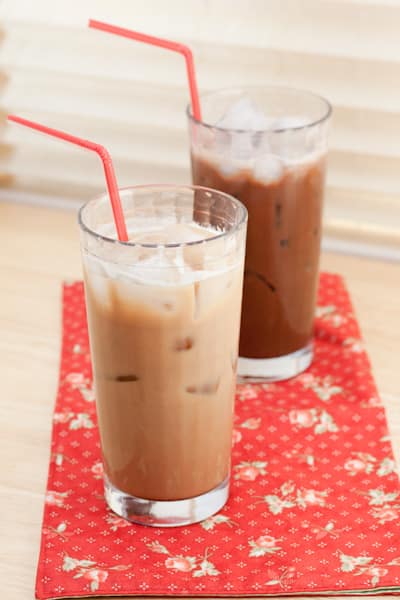 Two iced lattes with red straws.