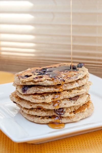 Maple syrup drizzling on a stack of blueberry pancakes.