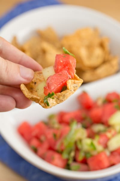 Scooping watermelon salsa with a tortilla chip.