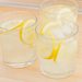 Three glasses of lemonade with lemon wheels to garnish.