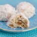 Mexican wedding cookies on a plate with a bite taken out of one.