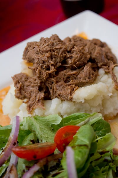 Beef goulash over mashed potatoes with a salad.
