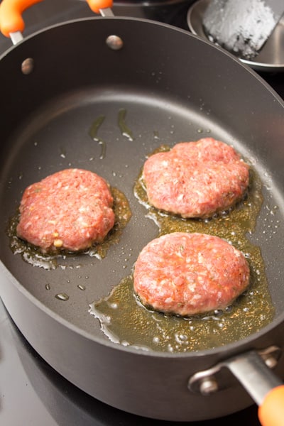 Sausage patties cooking in a skillet.