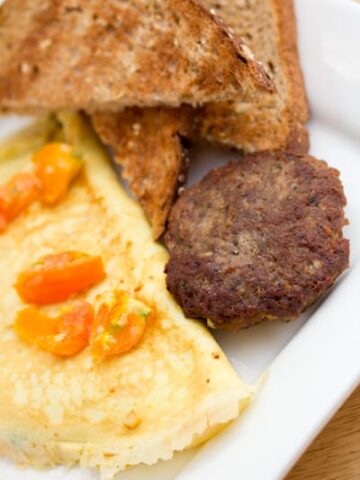 Omelette with tomatoes, sausage, and toast.