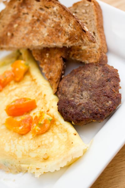 Omelette with tomatoes, sausage, and toast.