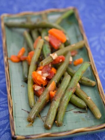Platter of green beans with tomato and carrot.