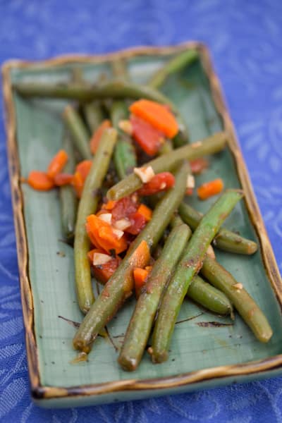 Platter of green beans with tomato and carrot.