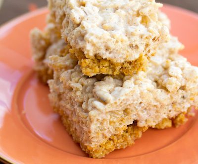 Pumpkin pie rice krispie treats stacked on top of each other on an orange plate.