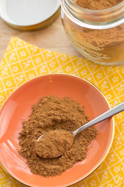 Pumpkin pie spice in a jar and on a plate with a spoon.