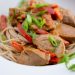 Szechuan pork over noodles in a bowl.
