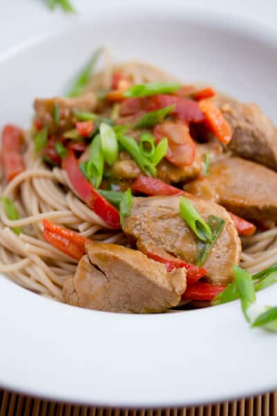 Szechuan pork over noodles in a bowl.