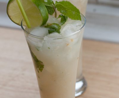 Two lychee mojitos garnished with mint and lime.