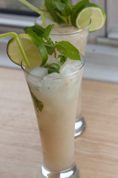 Two lychee mojitos garnished with mint and lime.