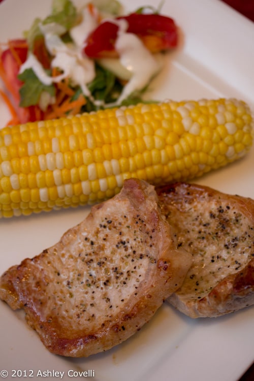 A plate of pork chops with corn and salad.