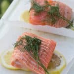 Salmon on parchment paper squares with lemon and fresh dill
