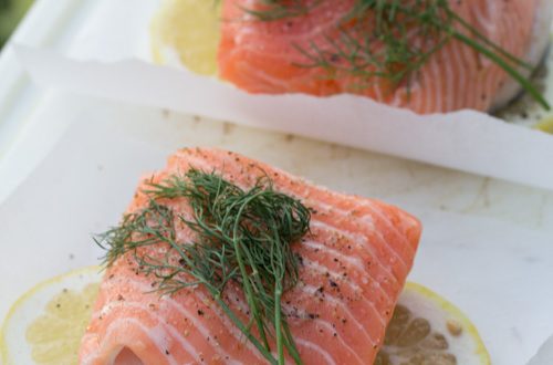 Salmon on parchment paper squares with lemon and fresh dill