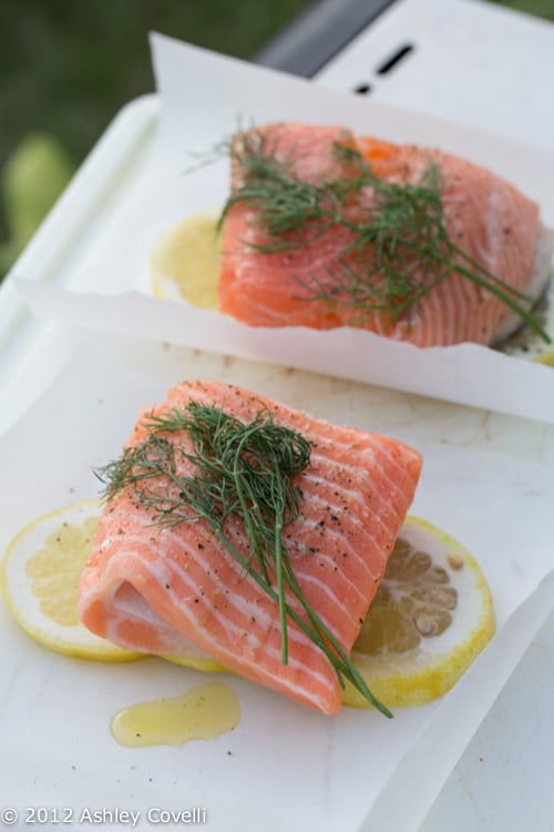 Salmon on parchment paper squares with lemon and fresh dill