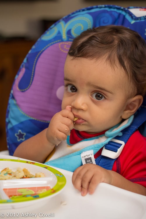 Baby eating in a high chair.