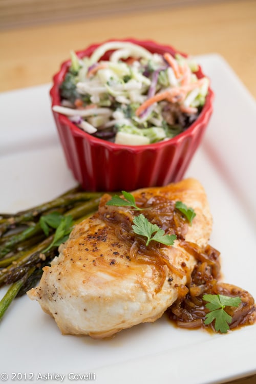 Chicken breast with sauce served with asparagus and cole slaw.