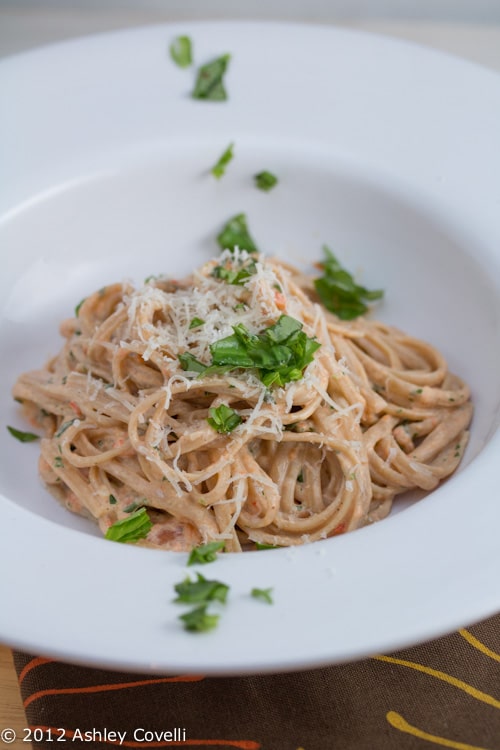 Bowl of pasta topped with Parmesan and parsley.