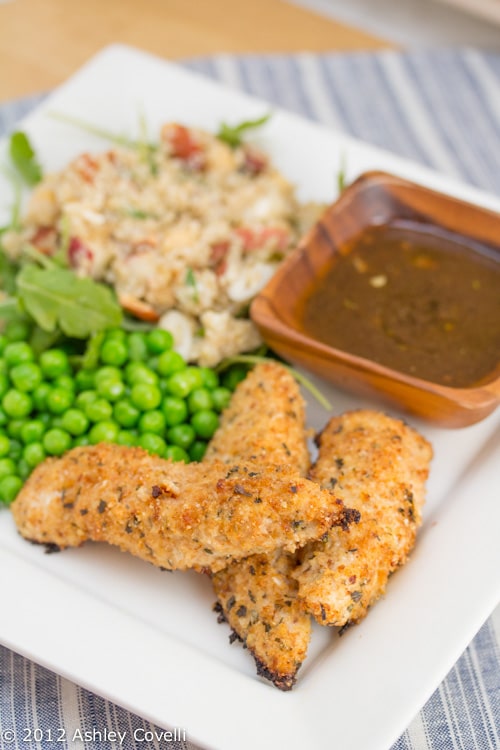 Chicken tenders on a plate with peas, dipping sauce, and quinoa salad.