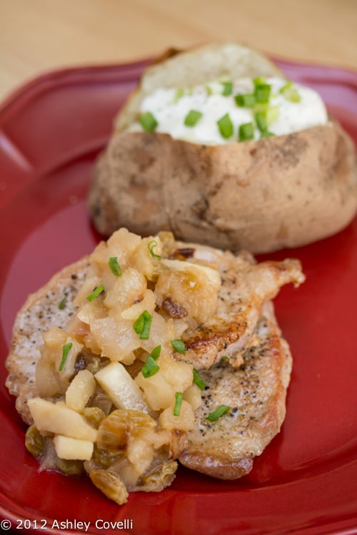 Pork chop topped with apple chutney served with a baked potato.