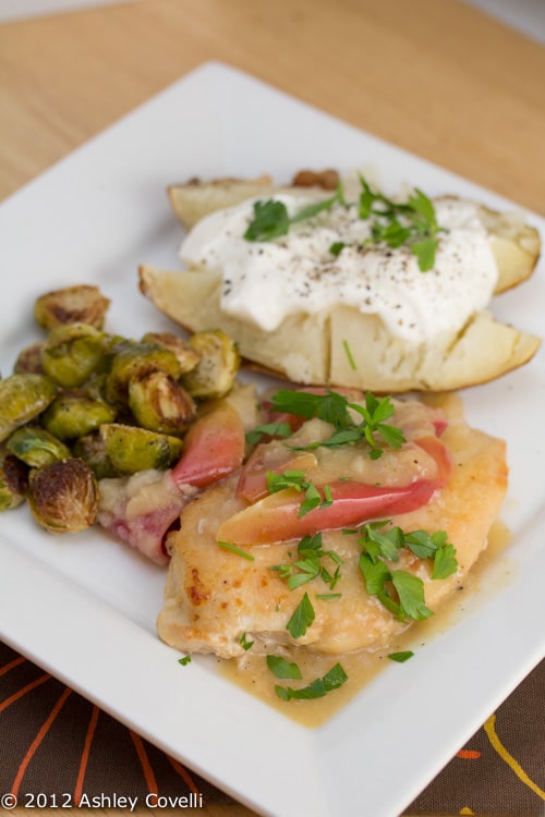 Chicken with apples, brussels sprouts, and a baked potato.