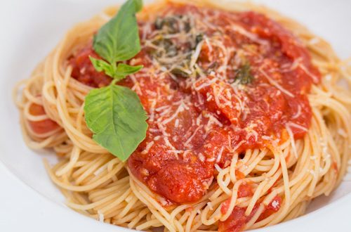 A plate of spaghetti topped with tomato sauce and basil.
