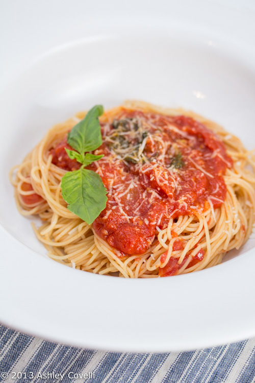 A plate of spaghetti topped with tomato sauce and basil.